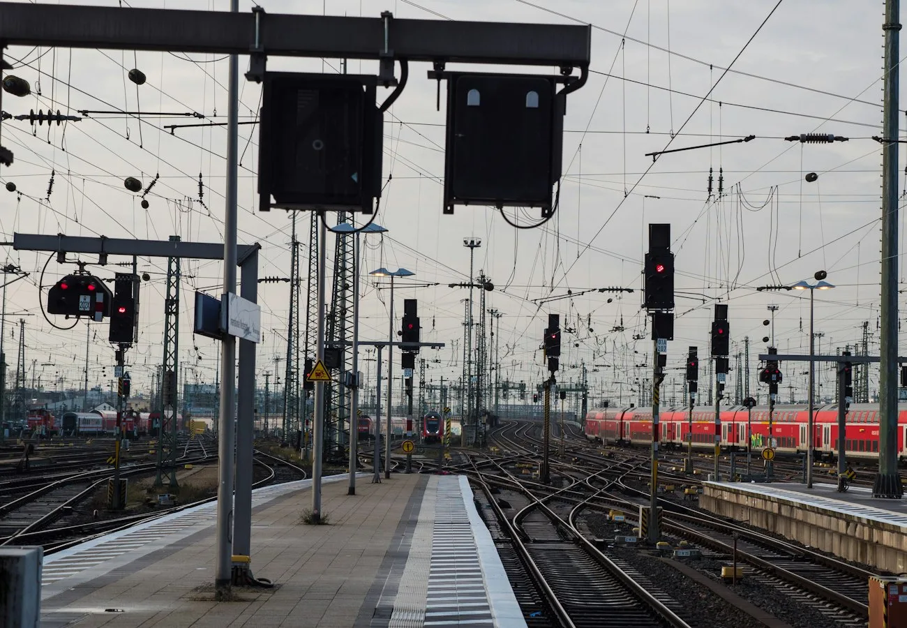 Gleisvorfeld des Frankfurter Hauptbahnhofs mit Weichen, Signalen und Oberleitungen, rechts ein roter Regionalzug